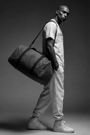 Man carrying a duffel bag against a dark background
