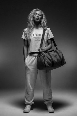 Person holding a duffel bag against a dark background