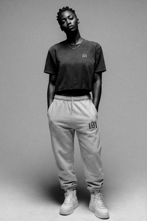 Person wearing a black t-shirt and gray sweatpants with a logo on a gray background