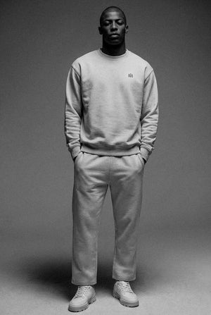 Person wearing a gray sweatshirt and pants on a plain background