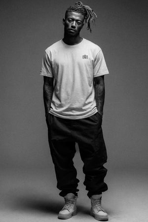 Person wearing a plain t-shirt and dark pants on a gray background