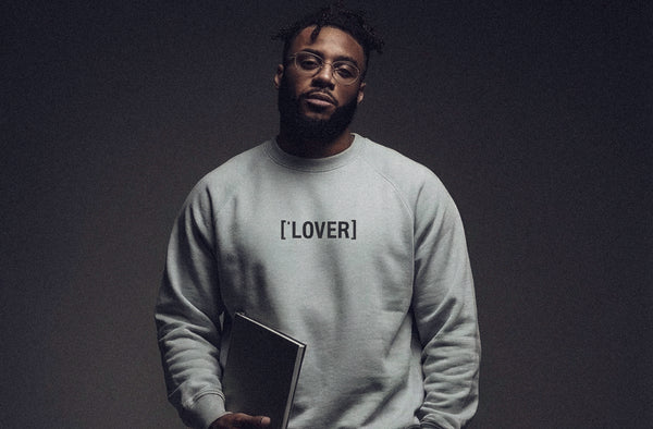 Model wearing ['LOVER]™ sweatshirt in soft neutral color, minimal studio setting