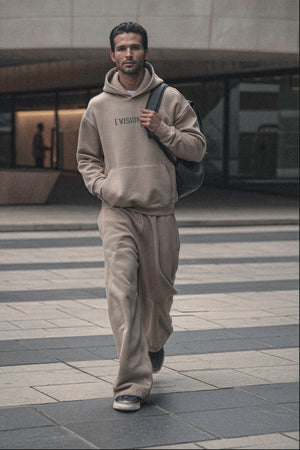 Man walking on a city street wearing a gray hoodie and beige pants.