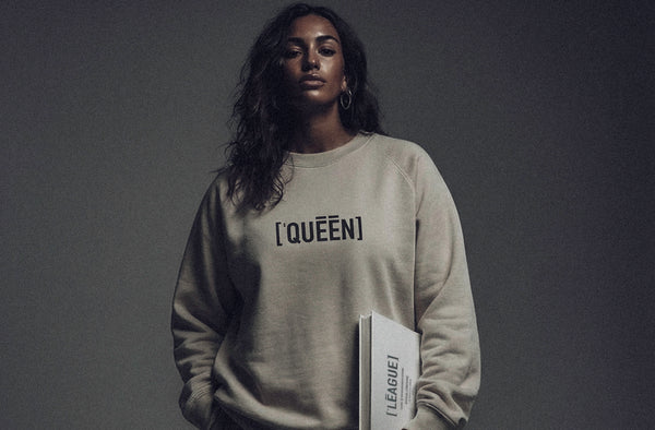 Model wearing ['QUEEN]™ sweatshirt in neutral tone, clean studio lighting