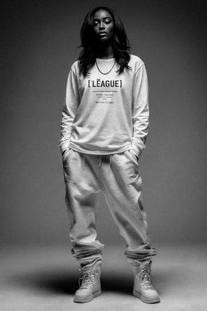 Person wearing a long-sleeve shirt with text and pants on a gray background