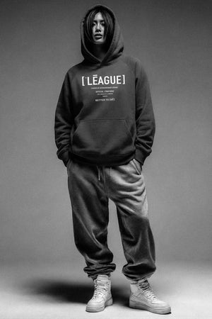 Person wearing a black hoodie with 'LEAGUE' branding on a gray background