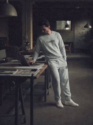 Person wearing a sweatshirt with 'LOVER' printed on it, standing in a dimly lit room.